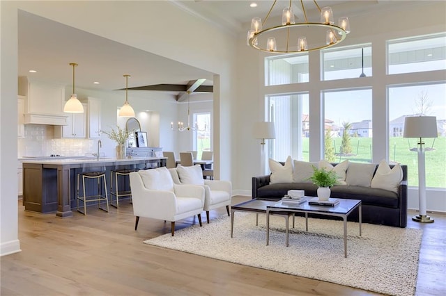 living room featuring sink, beam ceiling, light hardwood / wood-style flooring, and a chandelier