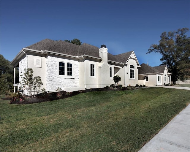 view of front of property with stone siding, roof with shingles, a chimney, and a front yard