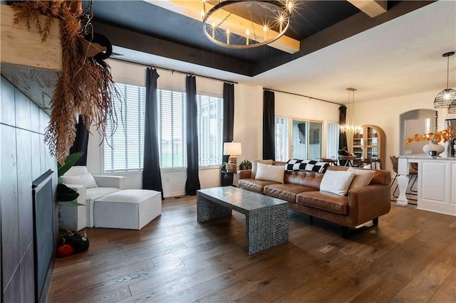 living area featuring a raised ceiling, dark wood-style floors, and a chandelier