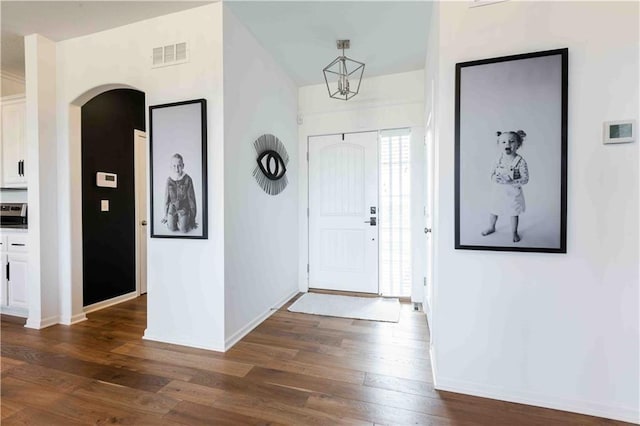 entrance foyer with visible vents, arched walkways, baseboards, and dark wood-type flooring