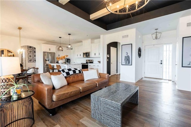 living room with an inviting chandelier, arched walkways, a tray ceiling, visible vents, and dark wood-style floors