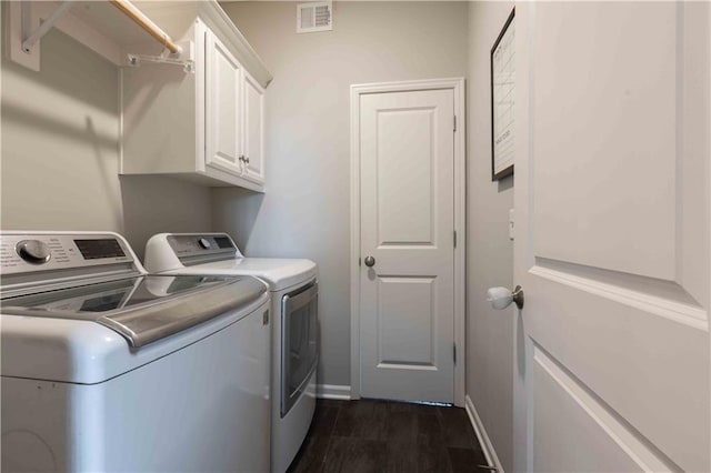 clothes washing area featuring visible vents, washing machine and dryer, dark wood finished floors, cabinet space, and baseboards