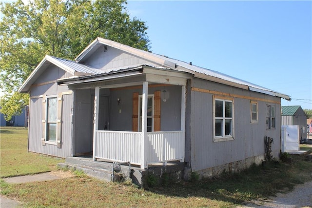 view of side of property featuring covered porch and a lawn