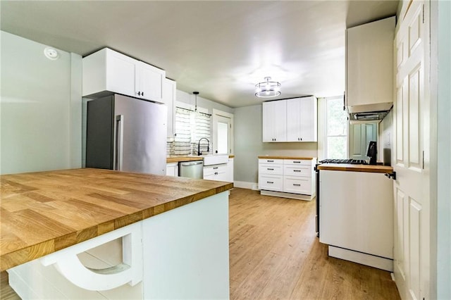 kitchen with wooden counters, appliances with stainless steel finishes, white cabinetry, decorative light fixtures, and kitchen peninsula