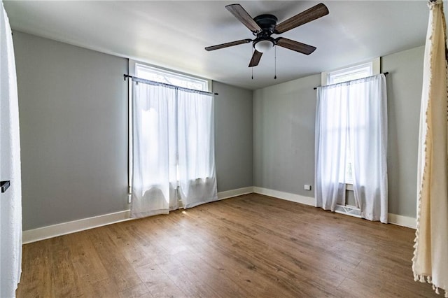 spare room with wood-type flooring, a healthy amount of sunlight, and ceiling fan