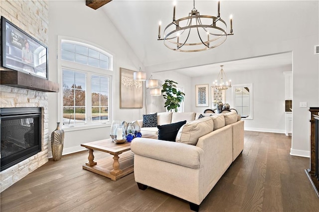 living area with beam ceiling, dark wood finished floors, a fireplace, an inviting chandelier, and baseboards
