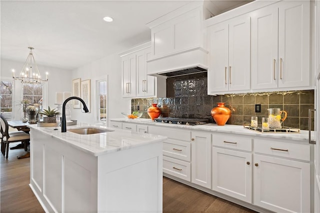 kitchen with a sink, white cabinetry, an island with sink, decorative light fixtures, and stainless steel gas stovetop