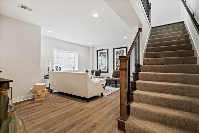 living area with stairs, recessed lighting, visible vents, and wood finished floors