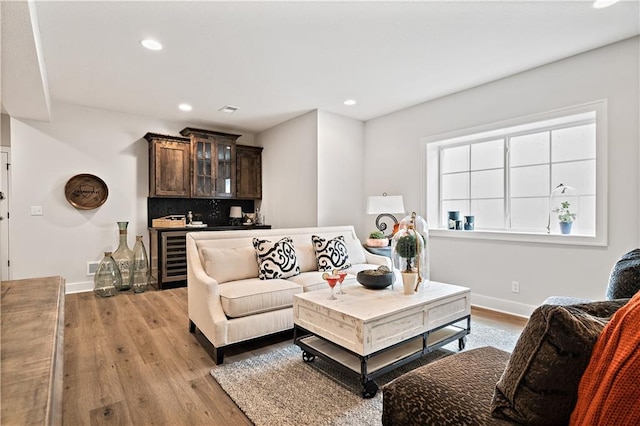 living room with beverage cooler, visible vents, baseboards, light wood-style flooring, and recessed lighting