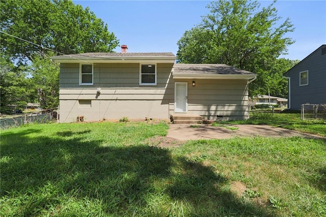 back of property featuring fence, a lawn, and a patio