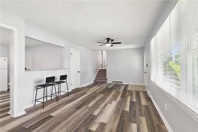 living room with visible vents, stairway, baseboards, and wood finished floors