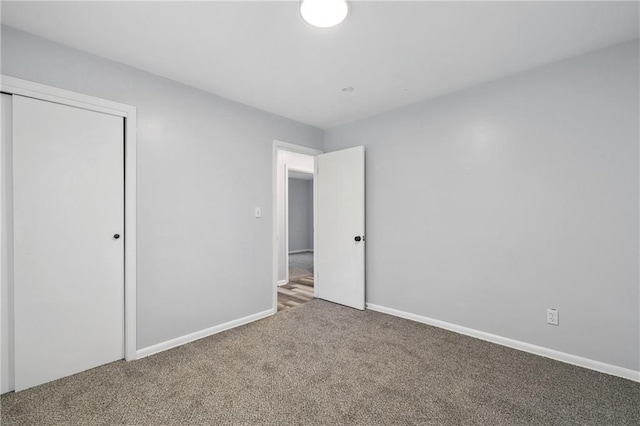 unfurnished bedroom featuring carpet floors, baseboards, and a closet