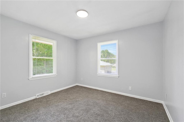 unfurnished room featuring visible vents, dark carpet, and baseboards