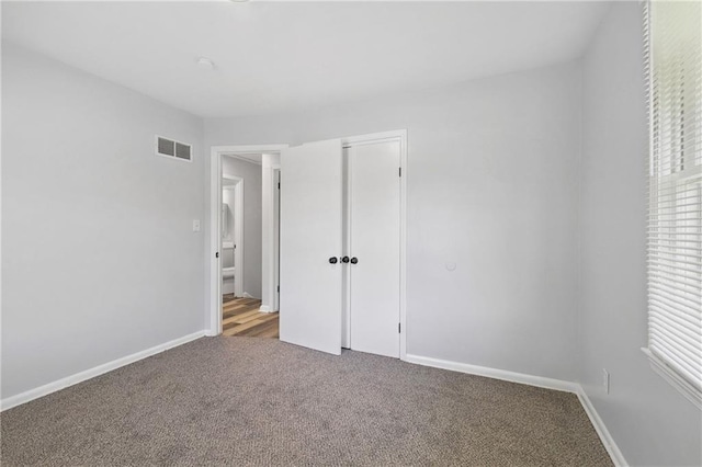 unfurnished bedroom featuring carpet, a closet, visible vents, and baseboards