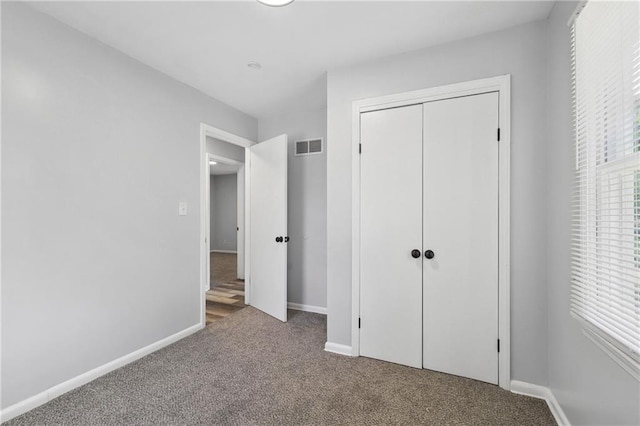 unfurnished bedroom with carpet, a closet, visible vents, and baseboards