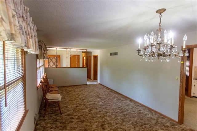 interior space featuring a chandelier, light carpet, and a textured ceiling