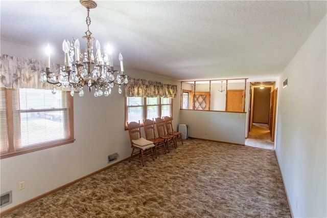 unfurnished dining area with a textured ceiling, carpet floors, and a chandelier