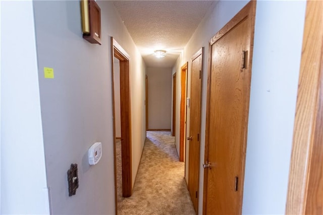 corridor with light carpet and a textured ceiling