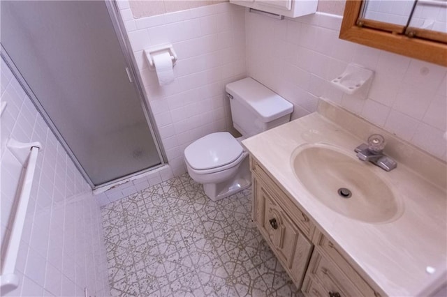 bathroom featuring vanity, a shower with door, tile walls, and toilet