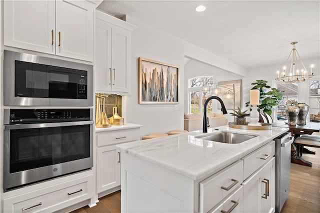 kitchen featuring stainless steel appliances, sink, an island with sink, white cabinetry, and dark wood-type flooring