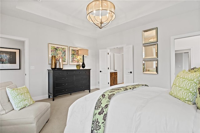 bedroom with ensuite bathroom, a chandelier, light carpet, and a tray ceiling