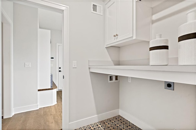 clothes washing area with electric dryer hookup, cabinets, and hardwood / wood-style floors