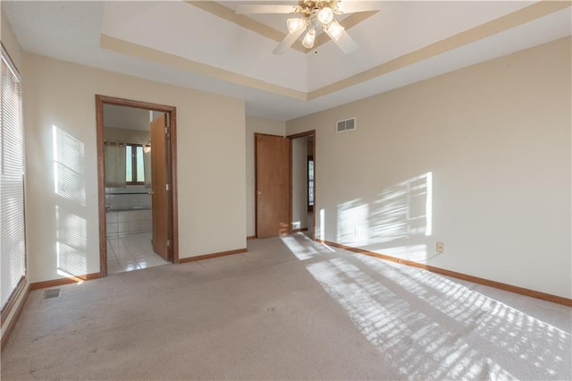 unfurnished room featuring ceiling fan, light carpet, and a raised ceiling