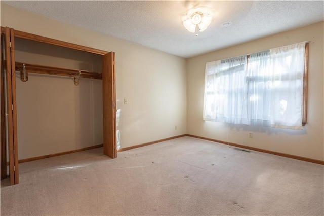 unfurnished bedroom featuring light carpet, a closet, and a textured ceiling