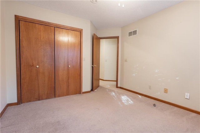 unfurnished bedroom with a closet and light carpet