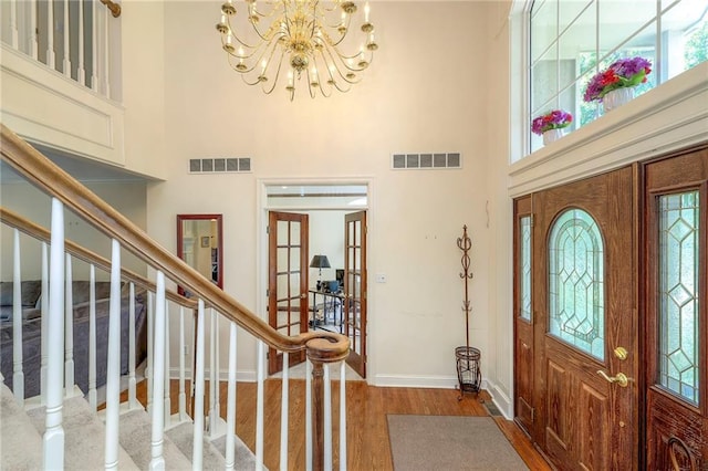 entrance foyer featuring a towering ceiling, hardwood / wood-style floors, and a notable chandelier