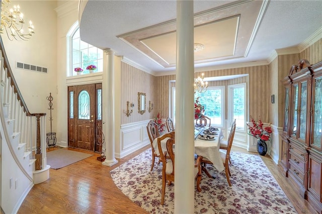 dining area with crown molding, a wealth of natural light, an inviting chandelier, and light hardwood / wood-style floors