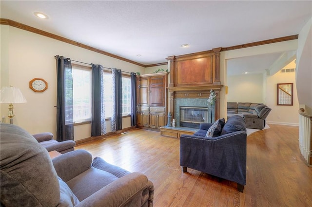 living room with ornamental molding, a high end fireplace, and light hardwood / wood-style flooring