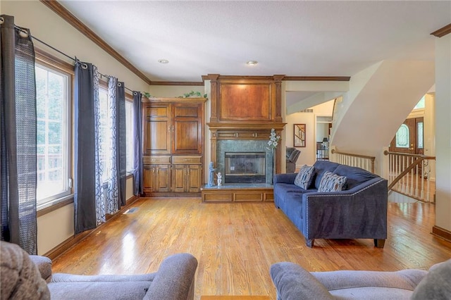 living room with a premium fireplace, plenty of natural light, ornamental molding, and light hardwood / wood-style floors