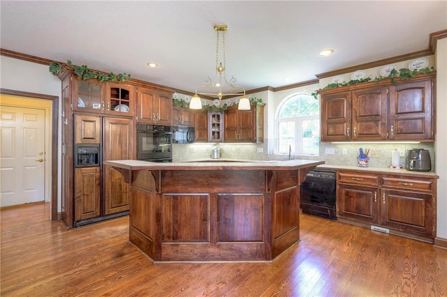 kitchen with dark hardwood / wood-style flooring, a center island, hanging light fixtures, and black appliances