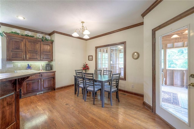 dining area with crown molding, plenty of natural light, and light wood-type flooring