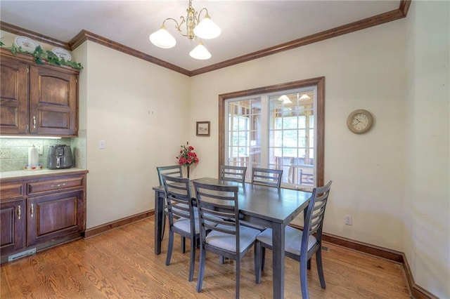 dining space featuring ornamental molding, a notable chandelier, and light wood-type flooring