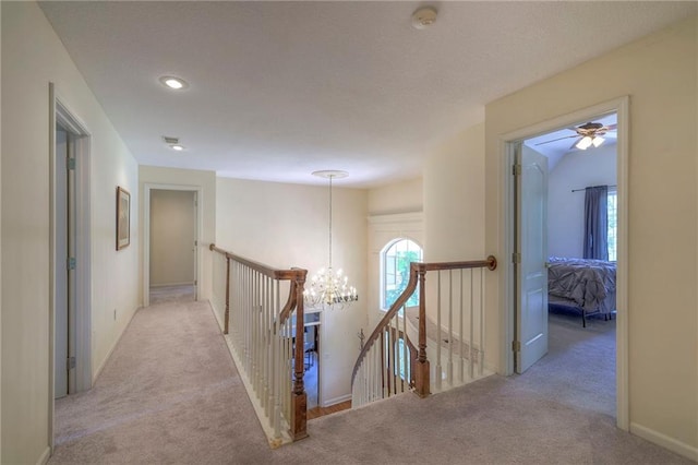 corridor featuring light colored carpet and a notable chandelier