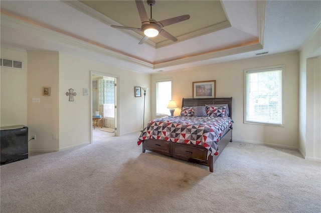 carpeted bedroom featuring connected bathroom, a tray ceiling, ornamental molding, and ceiling fan