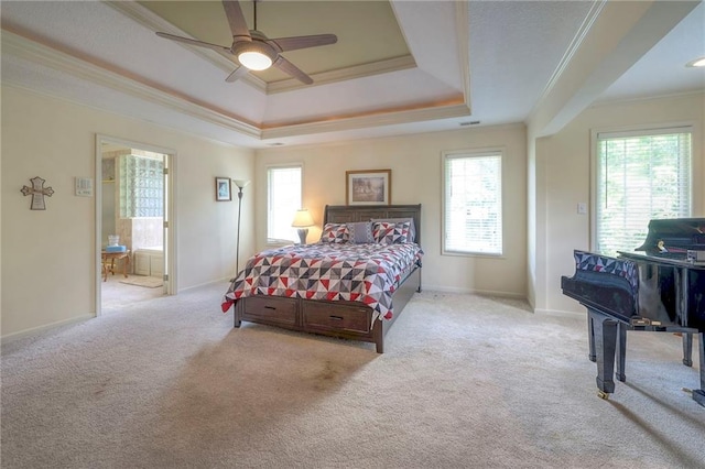 carpeted bedroom featuring connected bathroom, a tray ceiling, ornamental molding, and ceiling fan