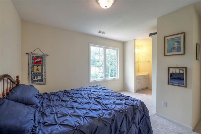 bedroom with ensuite bathroom and light carpet