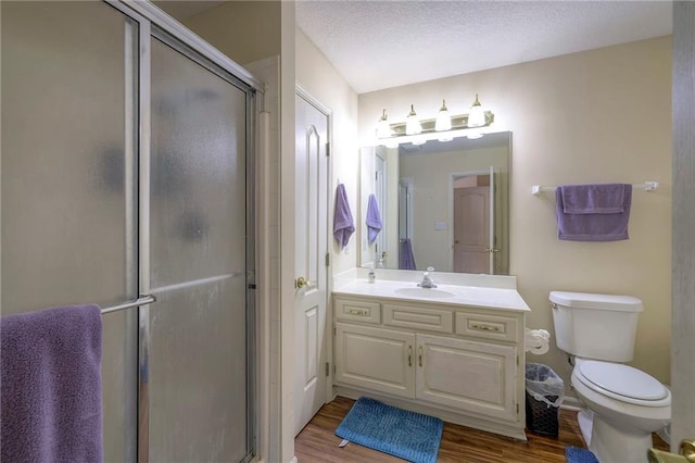 bathroom featuring toilet, a textured ceiling, vanity, a shower with door, and hardwood / wood-style flooring