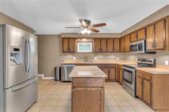 kitchen featuring stainless steel appliances, brown cabinets, light tile patterned flooring, and light countertops