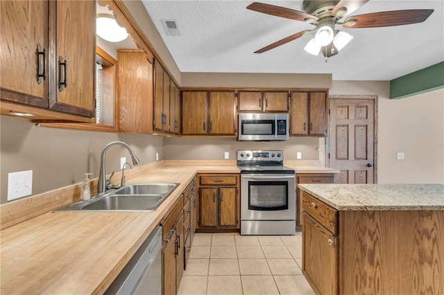 kitchen with a sink, stainless steel appliances, brown cabinets, and visible vents