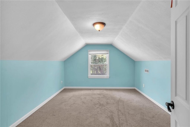 additional living space with vaulted ceiling, carpet flooring, baseboards, and a textured ceiling