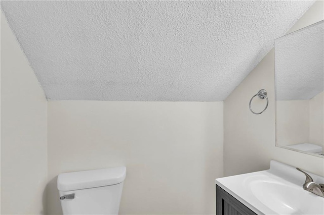 bathroom featuring lofted ceiling, a textured ceiling, and toilet