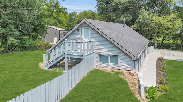 back of property with a yard, a shingled roof, stairs, and fence