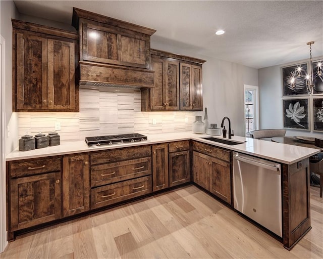 kitchen with stainless steel appliances, light hardwood / wood-style flooring, sink, and kitchen peninsula