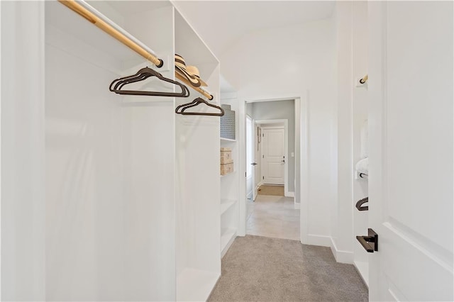 spacious closet with lofted ceiling and light colored carpet