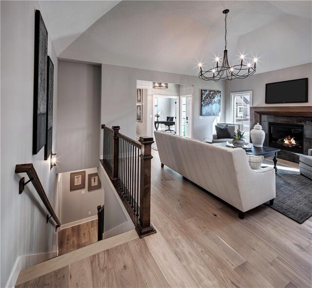 living room with lofted ceiling, light hardwood / wood-style floors, and an inviting chandelier