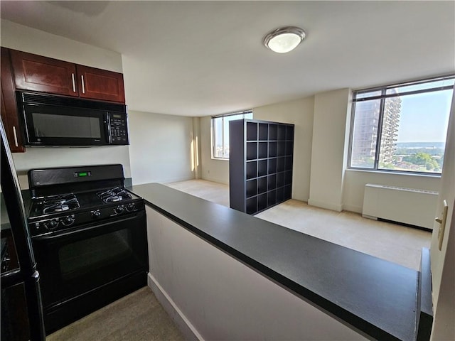 kitchen featuring black appliances, radiator, plenty of natural light, and light carpet